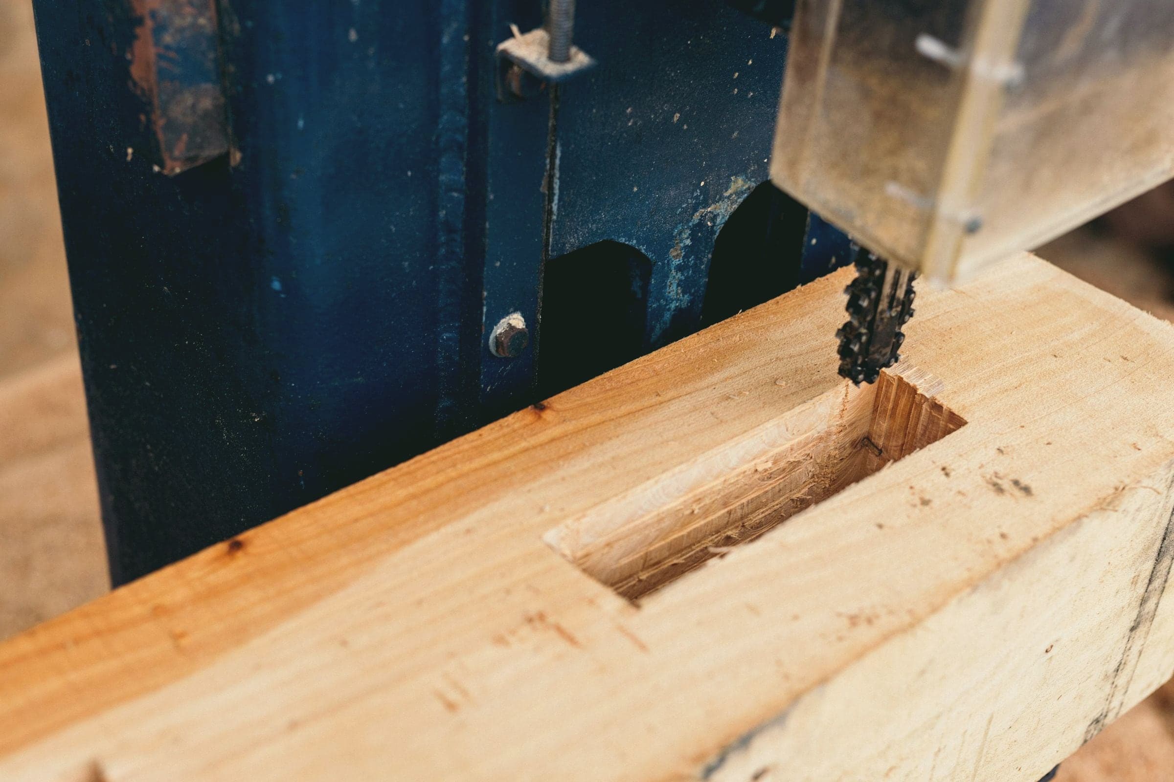 Une mortaise est creusée dans une pièce de bois.