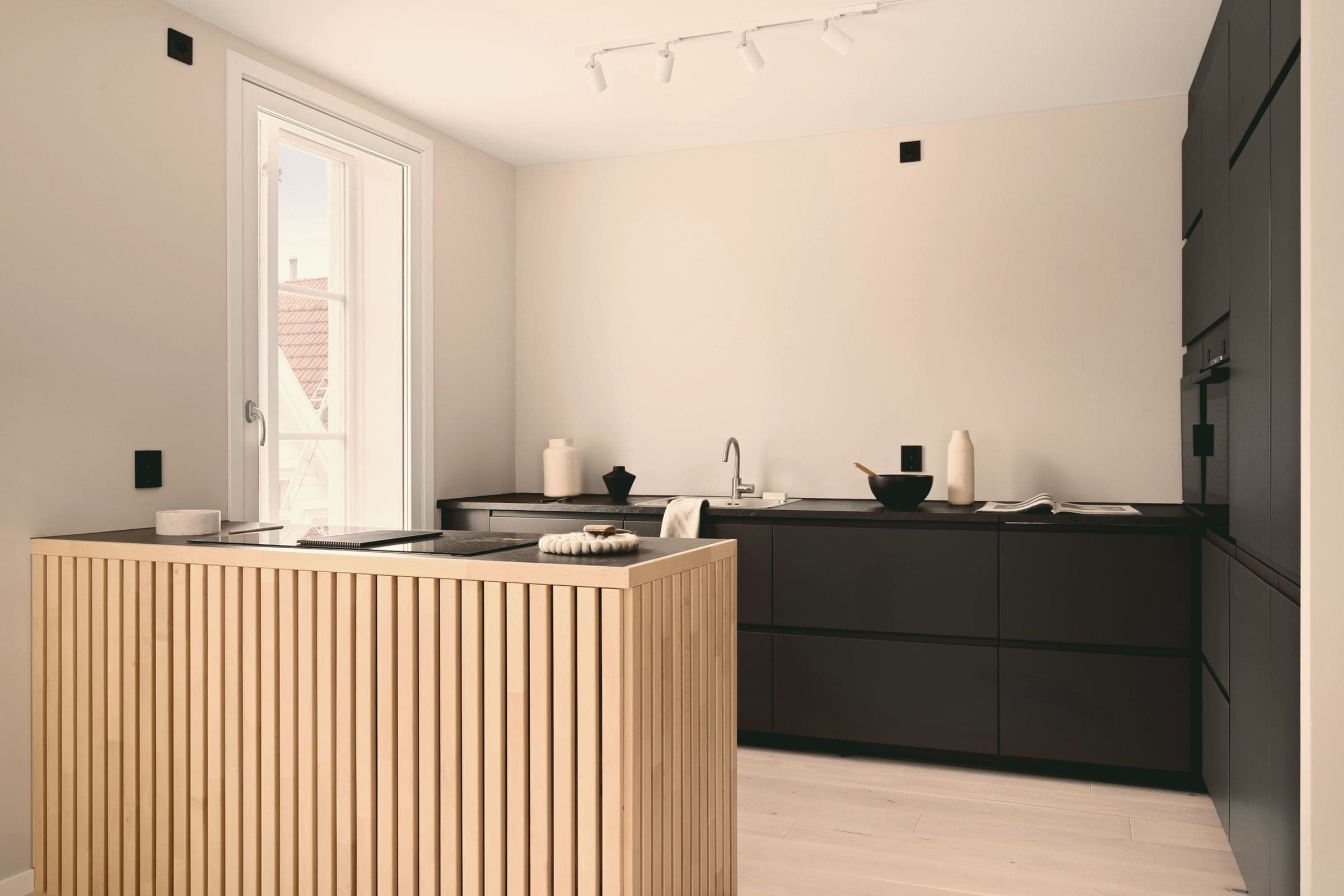 Cuisine avec un îlot en chêne cannelé et des façades noires.