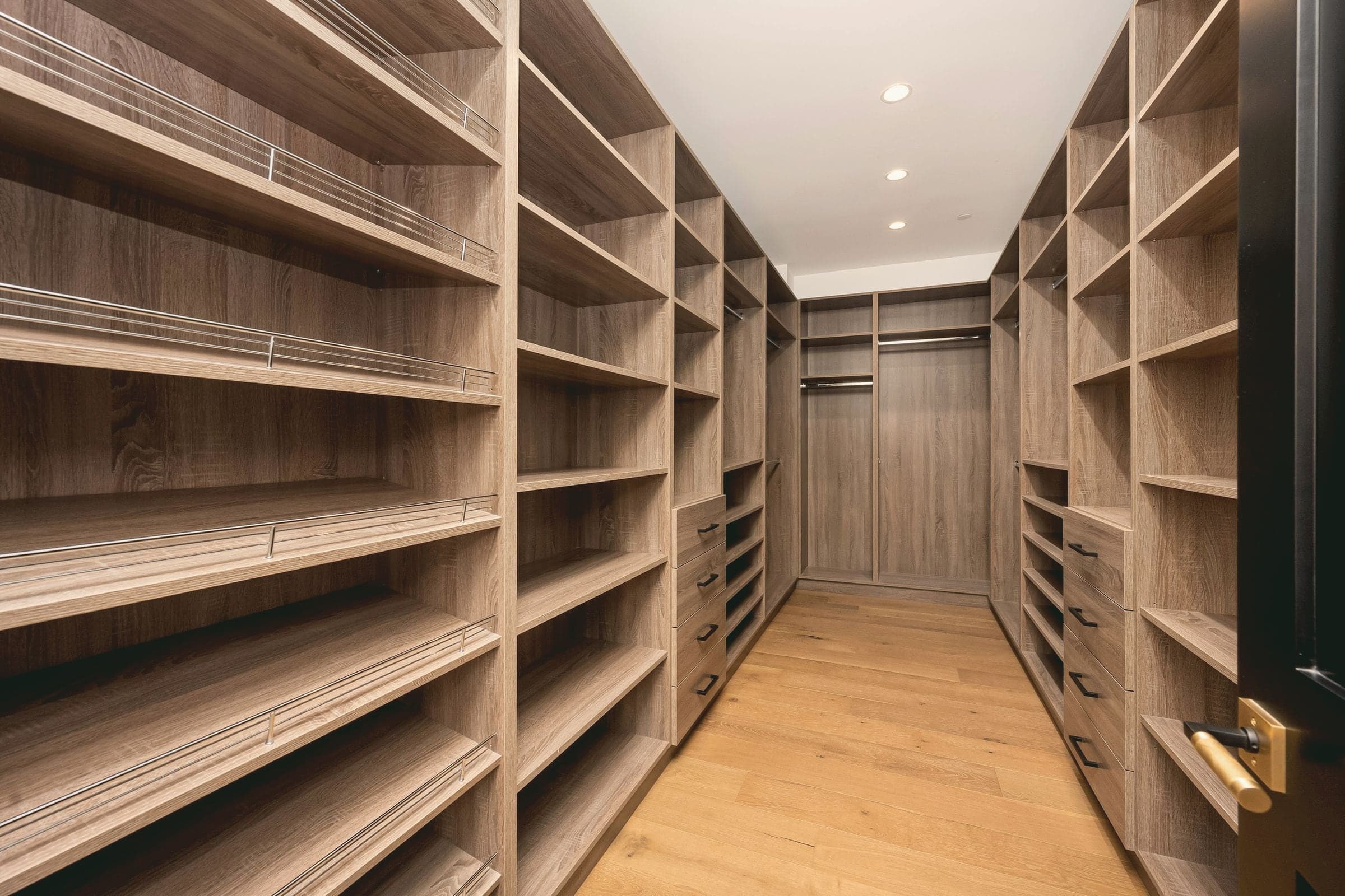 Dressing en bois clair : deux murs de tablettes et de tiroirs se font face.